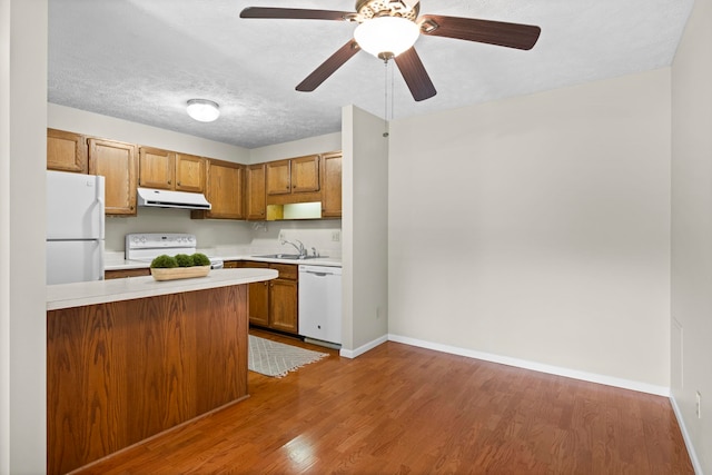 515 Georgetown Dr, Traverse City, MI 49684 - kitchen featuring white appliances, ventilation hood, a sink, light countertops, and brown cabinetry