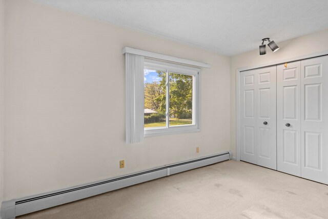515 Georgetown Dr, Traverse City, MI 49684 - unfurnished bedroom featuring a baseboard radiator, light colored carpet, and a closet