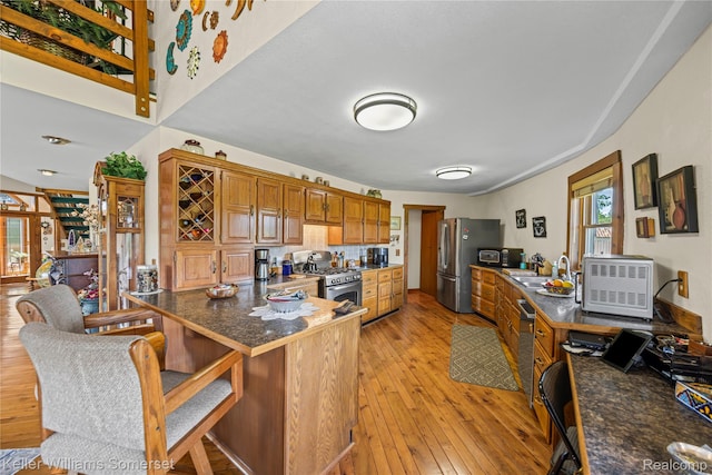 2637 E 7th Rd, Roscommon, MI 48653 - kitchen with appliances with stainless steel finishes, light wood-type flooring, a peninsula, dark countertops, and brown cabinetry