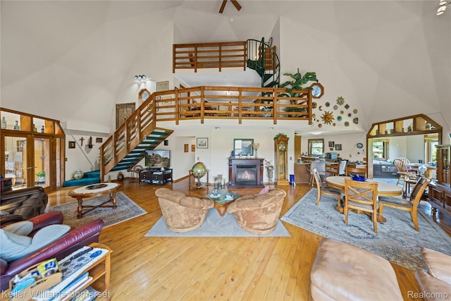 2637 E 7th Rd, Roscommon, MI 48653 - living area featuring a towering ceiling, stairway, wood-type flooring, a glass covered fireplace, and ceiling fan