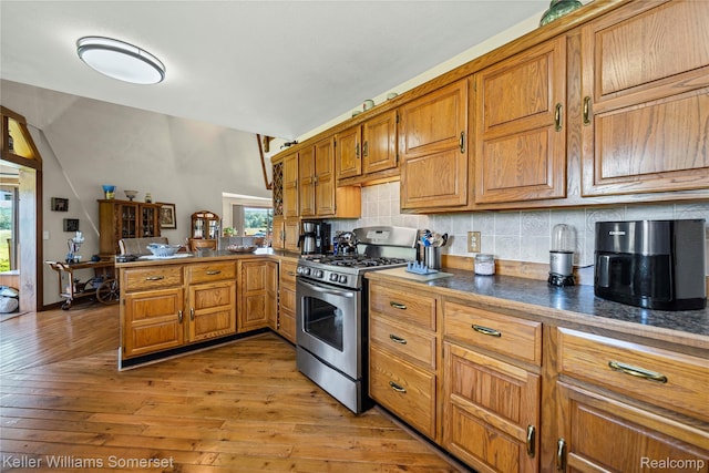 2637 E 7th Rd, Roscommon, MI 48653 - kitchen featuring gas stove, backsplash, a peninsula, brown cabinets, and light wood finished floors