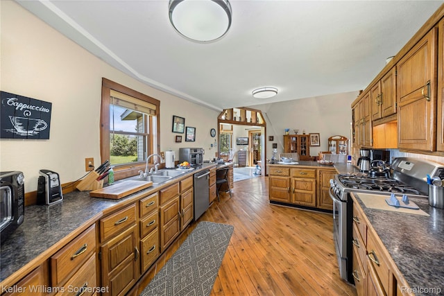 2637 E 7th Rd, Roscommon, MI 48653 - kitchen with appliances with stainless steel finishes, brown cabinetry, dark countertops, light wood-style floors, and a peninsula