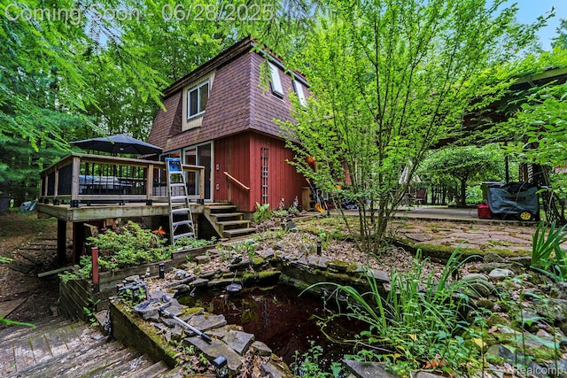 3030 Stanton Rd, Oxford, MI 48371 - exterior space featuring a wooden deck, a small pond, roof with shingles, and mansard roof