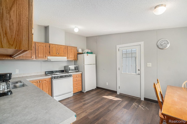12342 N Mackinaw Hwy, Carp Lake, MI 49718 - kitchen with white appliances, under cabinet range hood, dark wood-style floors, light countertops, and a textured ceiling