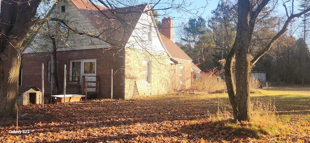 1701 Home Dr, Fairview, MI 48621 - view of side of property featuring a chimney and brick siding