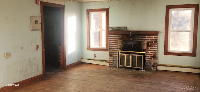 1701 Home Dr, Fairview, MI 48621 - unfurnished living room featuring baseboard heating, wood finished floors, a fireplace, and baseboards