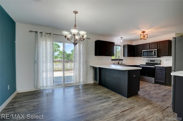 11468 Grand Oaks Dr, Clio, MI 48420 - kitchen featuring appliances with stainless steel finishes, a chandelier, tasteful backsplash, light countertops, and a sink