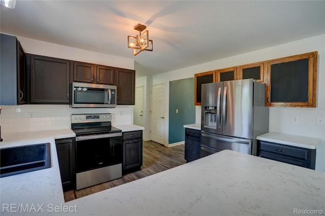 11468 Grand Oaks Dr, Clio, MI 48420 - kitchen featuring appliances with stainless steel finishes, dark wood-style flooring, backsplash, glass insert cabinets, and light stone countertops
