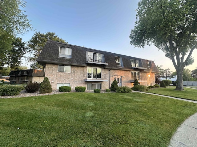 101 Provincial Ct, Saginaw, MI 48638 - view of front of home with a balcony, mansard roof, a front yard, roof with shingles, and brick siding