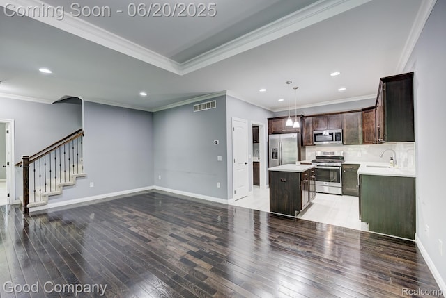 1724 Barrington Ct, Lake Orion, MI 48360 - kitchen with stainless steel appliances, light wood-style floors, dark brown cabinets, a kitchen island, and crown molding