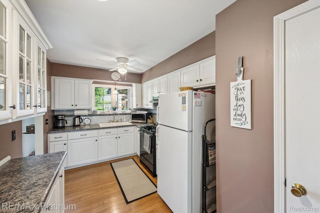 12132 Lexington Dr Unit 2, South Lyon, MI 48178 - kitchen featuring freestanding refrigerator, black stove, stainless steel microwave, a sink, and dark countertops