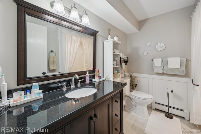 12132 Lexington Dr Unit 2, South Lyon, MI 48178 - bathroom featuring baseboard heating, wainscoting, vanity, toilet, and a decorative wall