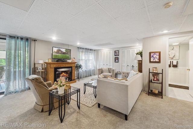 12132 Lexington Dr Unit 2, South Lyon, MI 48178 - living room featuring a drop ceiling, light colored carpet, and a lit fireplace