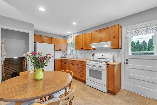 3622 Cushing Ct, Dexter, MI 48130 - kitchen featuring white appliances, under cabinet range hood, a sink, decorative backsplash, and light countertops