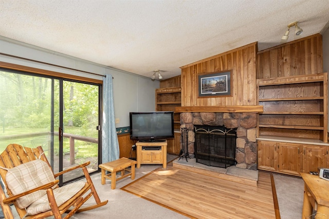 5665 N Sturgeon Rd, Midland, MI 48624 - living room with wood walls, a textured ceiling, a stone fireplace, and light wood-style flooring