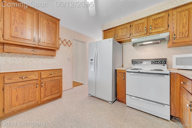 29628 Hoover Rd, Warren, MI 48093 - kitchen with white appliances, under cabinet range hood, wallpapered walls, light countertops, and brown cabinetry