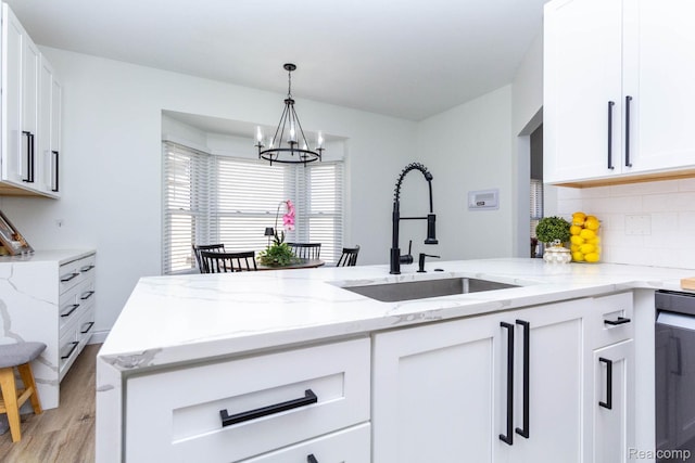 62874 Walker Ct Unit 17, Washington, MI 48094 - kitchen with a chandelier, light wood finished floors, white cabinetry, decorative backsplash, and light stone counters