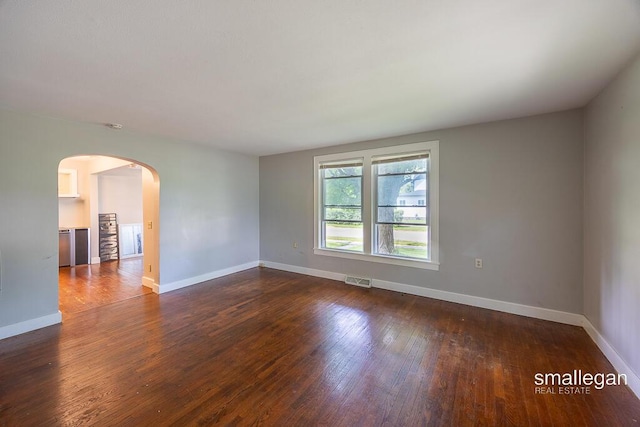 186 N Elm St, Sparta, MI 49345 - spare room featuring arched walkways, dark wood-style flooring, and baseboards