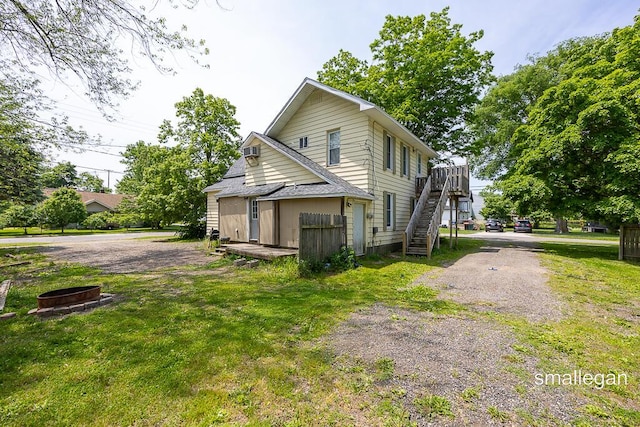 186 N Elm St, Sparta, MI 49345 - view of home's exterior with stairway, an outdoor fire pit, a deck, and a lawn