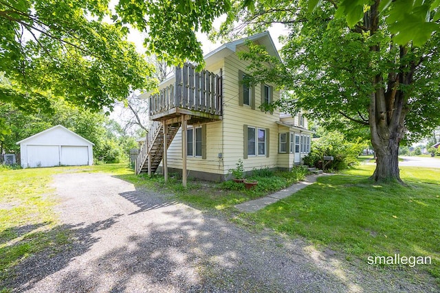 186 N Elm St, Sparta, MI 49345 - view of side of property featuring stairs, a detached garage, an outbuilding, a lawn, and a deck