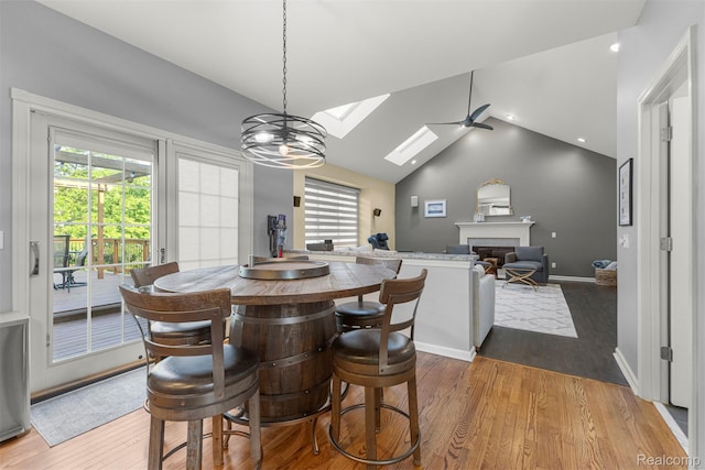 4991 Knollcrest Ct, Commerce Twp, MI 48382 - dining area with a fireplace, a skylight, light wood-type flooring, lofted ceiling, and a ceiling fan
