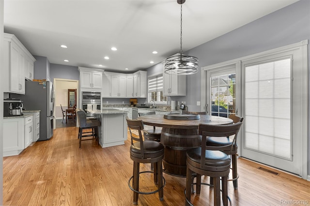 4991 Knollcrest Ct, Commerce Twp, MI 48382 - kitchen with a kitchen island, a kitchen bar, stainless steel appliances, recessed lighting, and white cabinetry