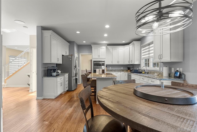 4991 Knollcrest Ct, Commerce Twp, MI 48382 - kitchen with appliances with stainless steel finishes, light wood-type flooring, recessed lighting, a center island, and white cabinets