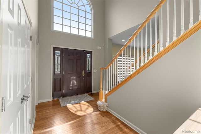 4991 Knollcrest Ct, Commerce Twp, MI 48382 - entrance foyer featuring wood finished floors, healthy amount of natural light, a high ceiling, and stairway