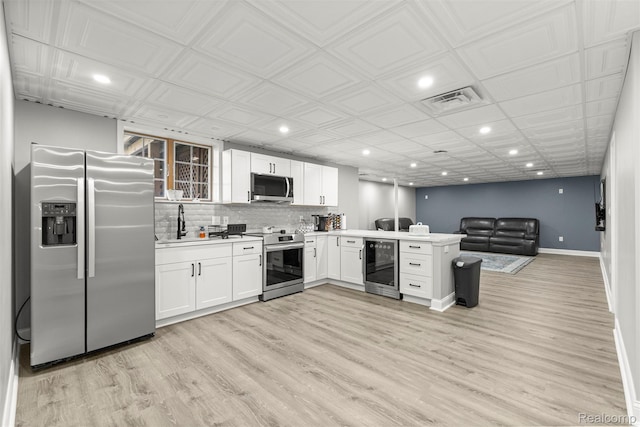 4991 Knollcrest Ct, Commerce Twp, MI 48382 - kitchen with appliances with stainless steel finishes, beverage cooler, recessed lighting, a peninsula, and white cabinetry