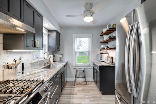 23069 Violet St, Farmington, MI 48336 - kitchen with appliances with stainless steel finishes, under cabinet range hood, light stone counters, light wood-style floors, and open shelves