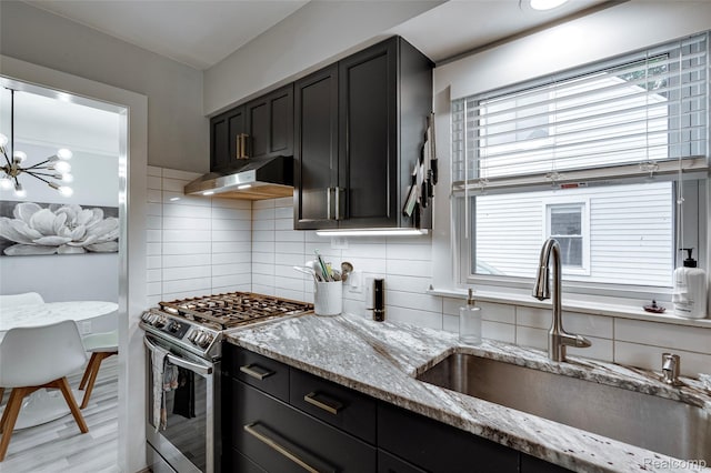 23069 Violet St, Farmington, MI 48336 - kitchen with stainless steel gas range oven, under cabinet range hood, dark cabinets, decorative backsplash, and plenty of natural light