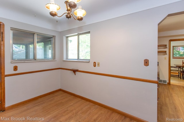 25695 York Rd, Royal Oak, MI 48067 - empty room featuring light wood-type flooring, a chandelier, and arched walkways
