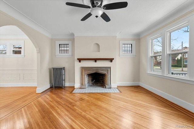 16525 Roselawn St, Detroit, MI 48221 - unfurnished living room with wood finished floors, a fireplace with flush hearth, arched walkways, ornamental molding, and radiator heating unit