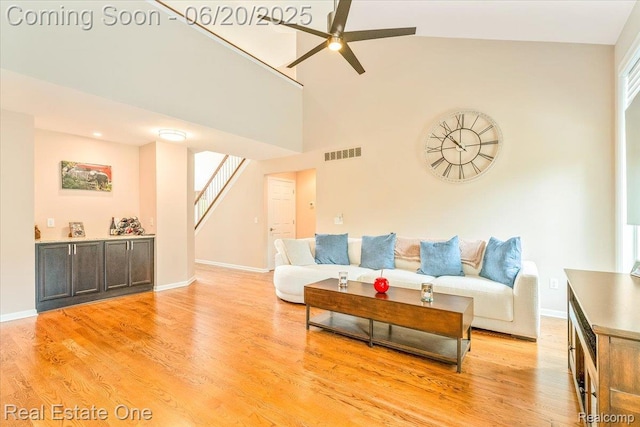 43543 Abbey Cir, Canton, MI 48187 - living room featuring a ceiling fan, stairway, light wood-style flooring, and a towering ceiling