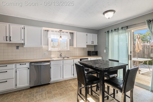 17325 Doris, Fraser, MI 48026 - kitchen featuring stainless steel dishwasher, white cabinets, black microwave, decorative backsplash, and light countertops