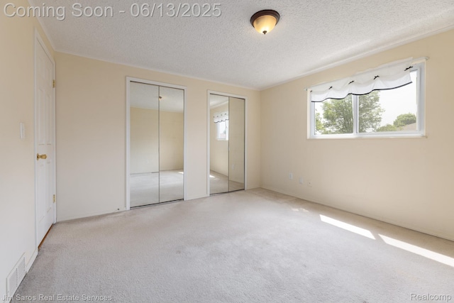 47425 Barbara Rd, Macomb, MI 48044 - unfurnished bedroom with multiple closets, carpet floors, and a textured ceiling