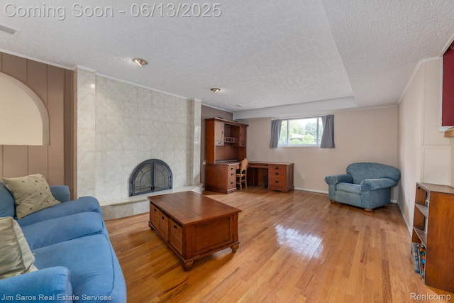 47425 Barbara Rd, Macomb, MI 48044 - living area featuring a textured ceiling, a tiled fireplace, light wood finished floors, and ornamental molding
