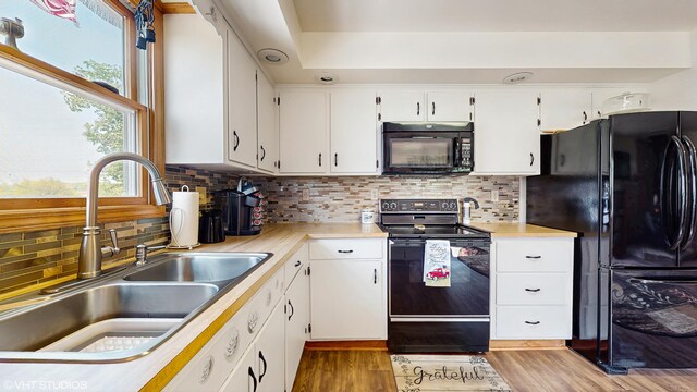 16486 Three Oaks Rd, Three Oaks, MI 49128 - kitchen with black appliances, a sink, light countertops, white cabinets, and wood finished floors