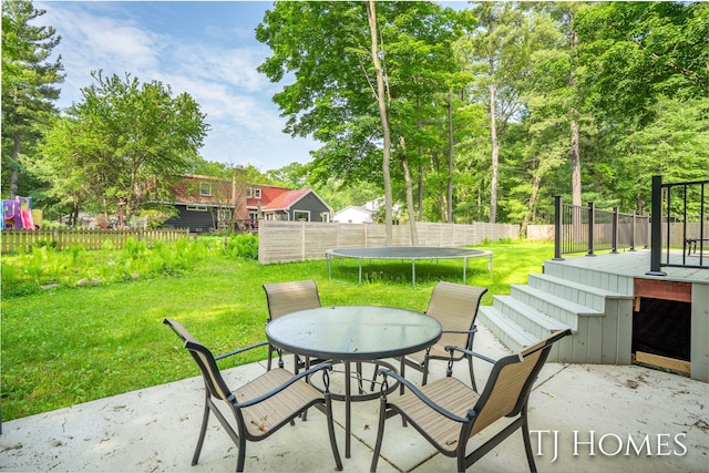2605 Shadowbrook Dr SE, Grand Rapids, MI 49546 - view of patio featuring a trampoline, outdoor dining space, and view of wooded area