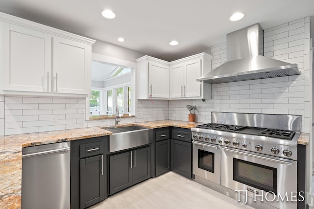 2605 Shadowbrook Dr SE, Grand Rapids, MI 49546 - kitchen with stainless steel appliances, wall chimney exhaust hood, a sink, white cabinetry, and recessed lighting