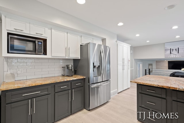2605 Shadowbrook Dr SE, Grand Rapids, MI 49546 - kitchen with appliances with stainless steel finishes, white cabinetry, tasteful backsplash, light wood finished floors, and recessed lighting