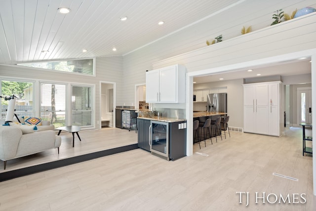 2605 Shadowbrook Dr SE, Grand Rapids, MI 49546 - kitchen featuring wine cooler, stainless steel fridge with ice dispenser, recessed lighting, a kitchen bar, and white cabinetry