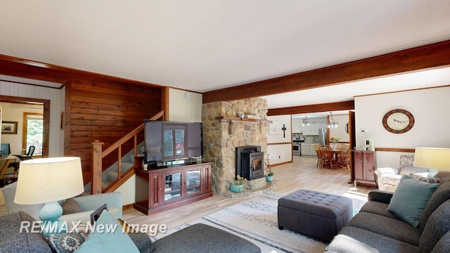 2258 High Rd, Roscommon, MI 48653 - living room featuring stairs, a wood stove, light wood-style flooring, wood walls, and beam ceiling