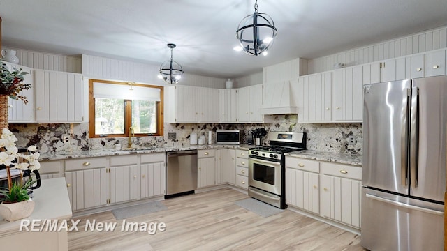 2258 High Rd, Roscommon, MI 48653 - kitchen featuring stainless steel appliances, custom exhaust hood, backsplash, light stone countertops, and light wood-style floors