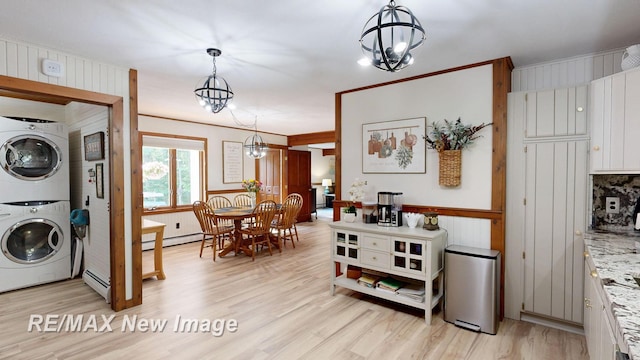 2258 High Rd, Roscommon, MI 48653 - laundry area featuring stacked washer / drying machine, a baseboard heating unit, a chandelier, and light wood-style floors