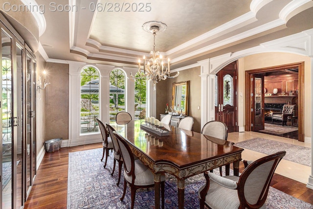 13123 Log Cabin Pt, Fenton, MI 48430 - dining space with a raised ceiling, decorative columns, a chandelier, wood finished floors, and crown molding