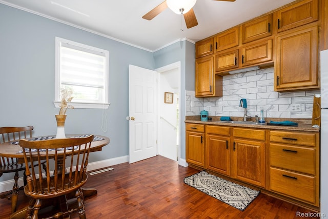 20470 Colman St S, Clinton Township, MI 48035 - kitchen with ceiling fan, ornamental molding, decorative backsplash, brown cabinetry, and dark wood-style floors