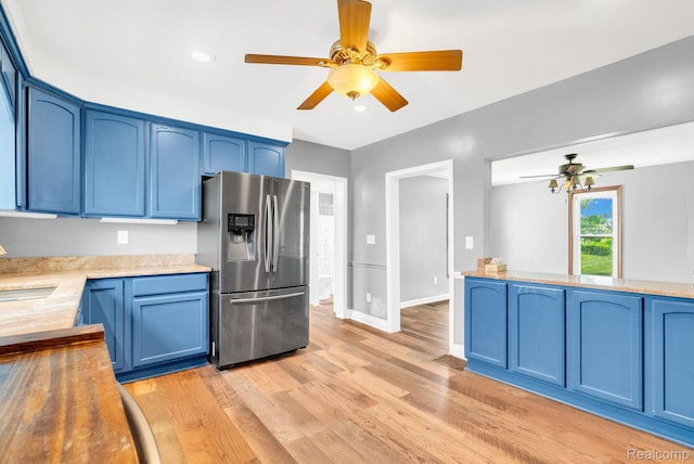 5276 Van Orden Rd, Webberville, MI 48892 - kitchen featuring stainless steel fridge, blue cabinetry, ceiling fan, light wood-style flooring, and light countertops
