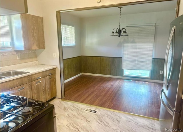 3461 Michael Ave, Warren, MI 48091 - kitchen featuring freestanding refrigerator, wainscoting, black range with gas cooktop, a chandelier, and brown cabinetry