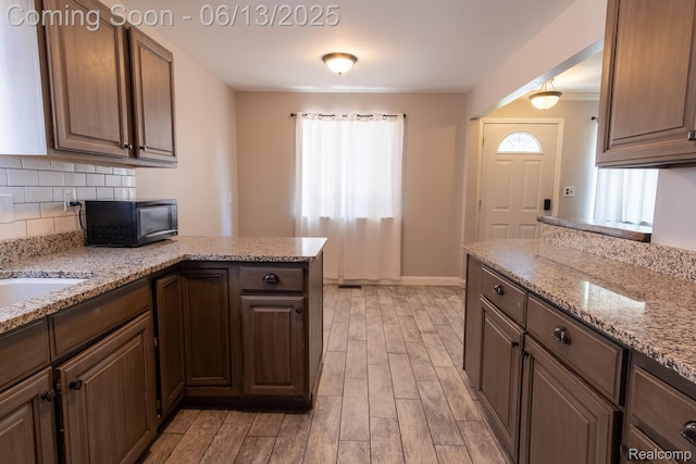 21806 Trombly St, Saint Clair Shores, MI 48080 - kitchen with light wood-style floors, a peninsula, tasteful backsplash, black microwave, and baseboards